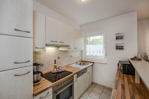 Eine moderne Küche mit hellen Holzschränken, einem Edelstahlherd und einem Fenster mit Blick.