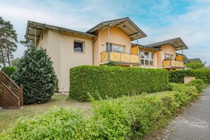 A residential building with a two-story structure, a covered balcony, and a well-maintained hedge. - Ferienwohnung Gestrandet - Ferienappartement mit Terrasse, Strandkorb, Wlan und Pkw-stellplatz (Koserow)