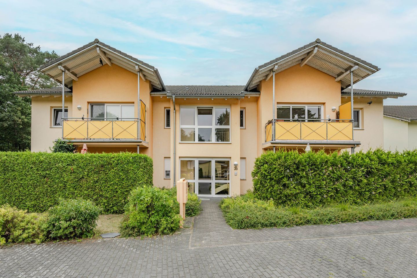 Een gebouw met twee verdiepingen, een symmetrische gevel, grote ramen en een centrale ingang.