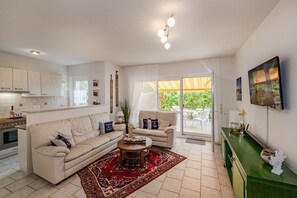 A modern living room with a beige sofa, a coffee table, and a red patterned rug.