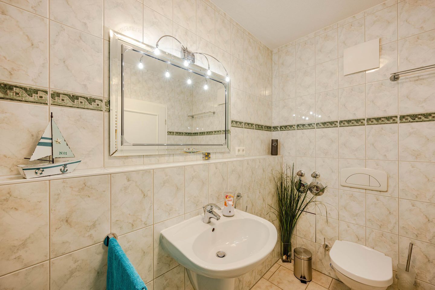 Une salle de bain avec un lavabo, des toilettes et un miroir avec éclairage.