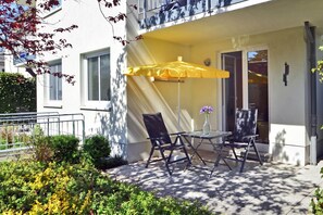 Un espace extérieur aménagé avec des sièges, comprenant un parasol jaune, deux chaises et une table.