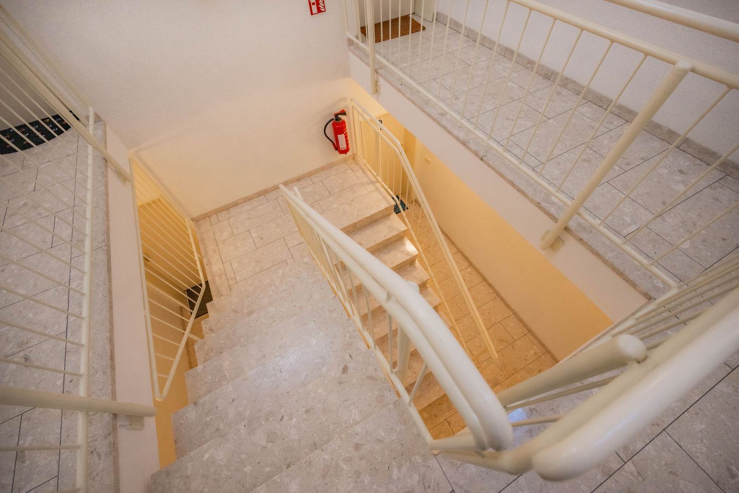 Ein mehrgeschossiges Interieur mit Treppe, Metallgeländern und einem Feuerlöscher.