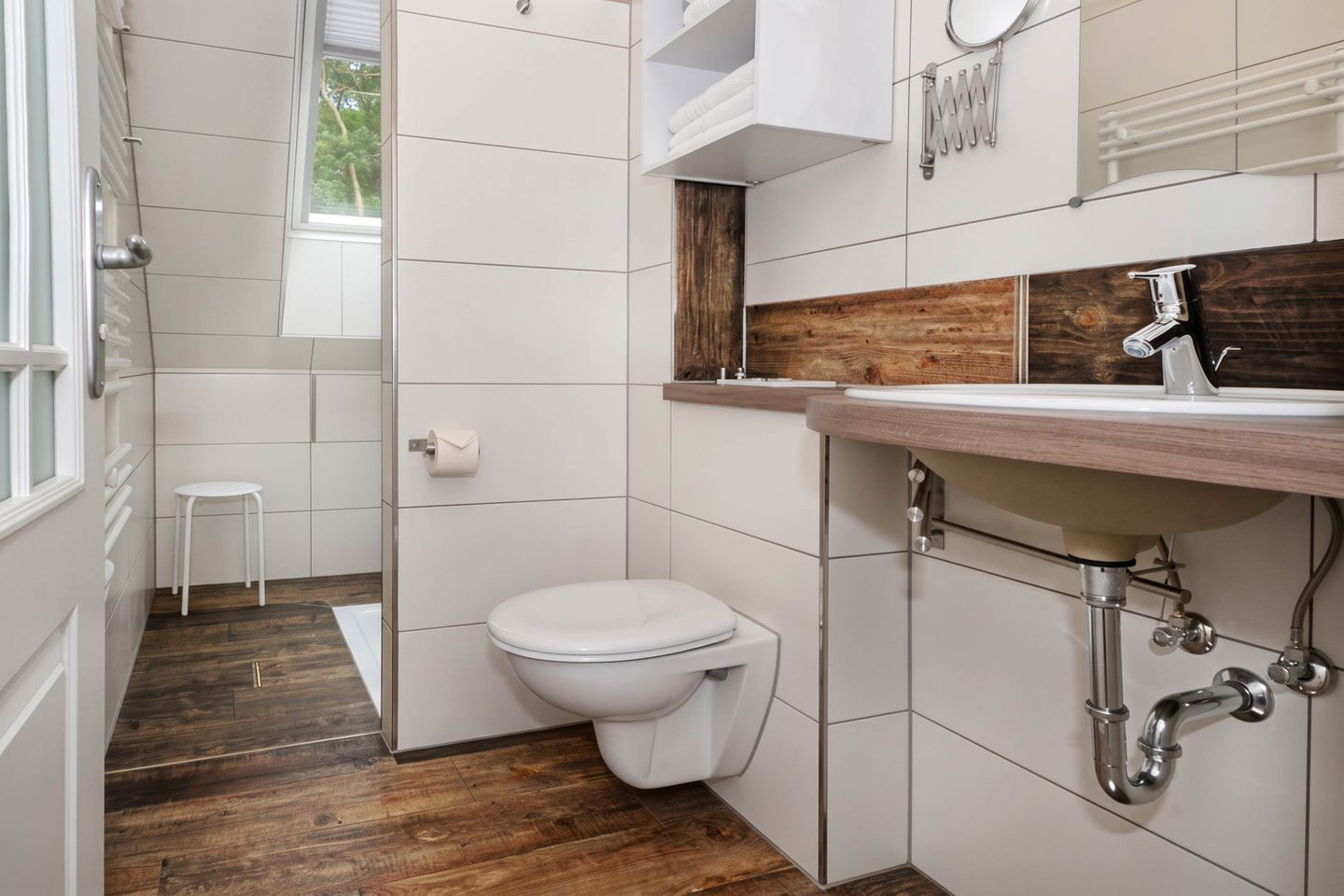 Un bagno con un water bianco, un mobile bagno in legno e una finestra.