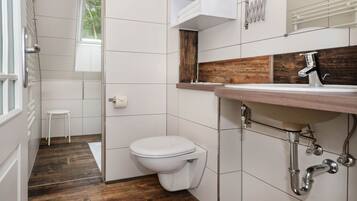 Un bagno con un water bianco, un mobile bagno in legno e una finestra.
