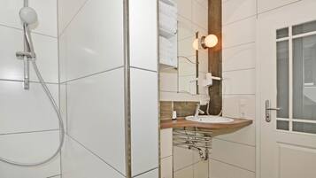 Ein modernes Badezimmer mit Dusche, Waschbecken und Spiegel.