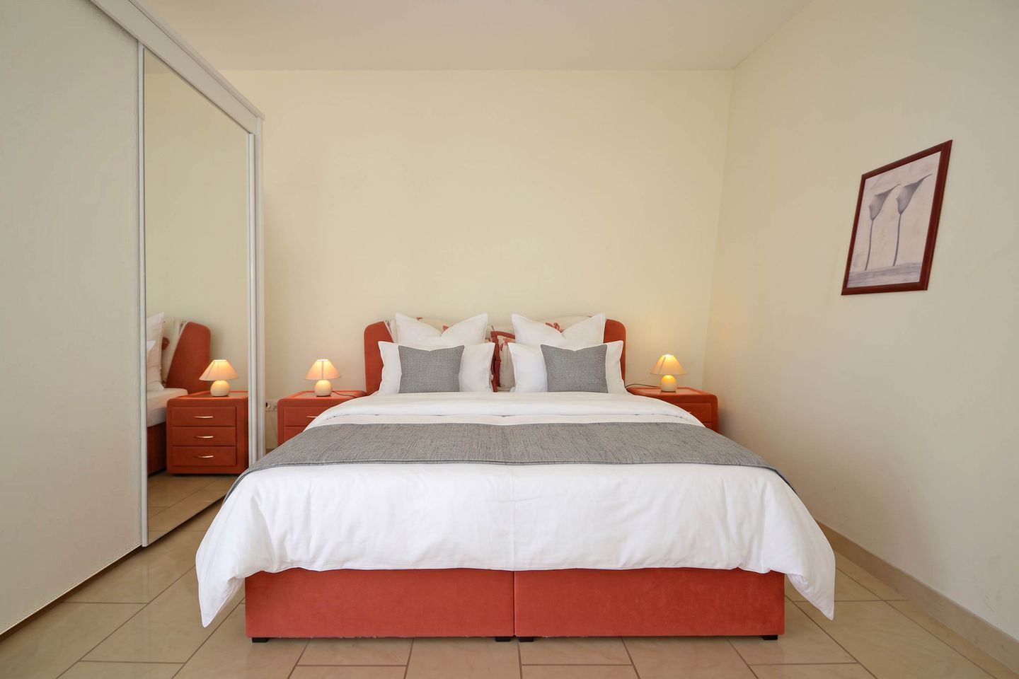 Ein Schlafzimmer mit einem Bett, zwei Nachttischen, einem Schminktisch und einem gerahmten Bild an der Wand.