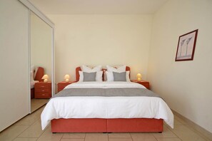 Ein Schlafzimmer mit einem Bett, zwei Nachttischen, einem Schminktisch und einem gerahmten Bild an der Wand.