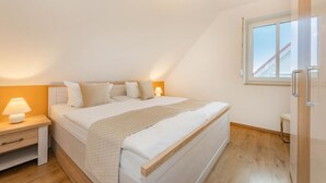 Ein Schlafzimmer mit Bett, Nachttischen, einem Fenster und Blick ins Freie.