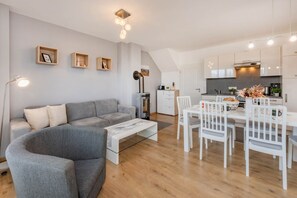 Un espacio habitable moderno con un sofá gris, una mesa de comedor blanca y sillas.
