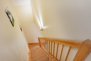 Una escalera de madera con barandilla que lleva a un piso superior.