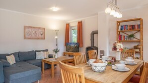 Ein gemütliches Wohnzimmer mit einer Couch, Esstisch, Stühlen, einem Kamin und einem Bücherregal.