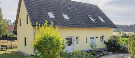 Een twee verdiepingen tellend huis met een schuin dak, meerdere ramen en een verharde oprit.