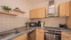 Eine moderne Küche mit Granit Arbeitsplatten, Edelstahlgeräten, Holzschränken und einem eingebauten Backofen.