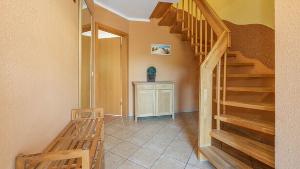 Ein Flur mit einer hölzernen Bank, einem Schrank und einer Treppe.