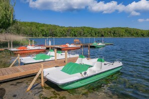 A lake with boats docked at wooden piers, surrounded by a forested area.