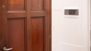 Eine Holztür mit Griff und Schlüsselloch, daneben eine weiße Wand mit Thermostatsteuerung.