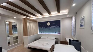 Ein modernes Hotelzimmer mit Bett, Nachttisch und einem großen Fenster mit Blick auf die Stadt.