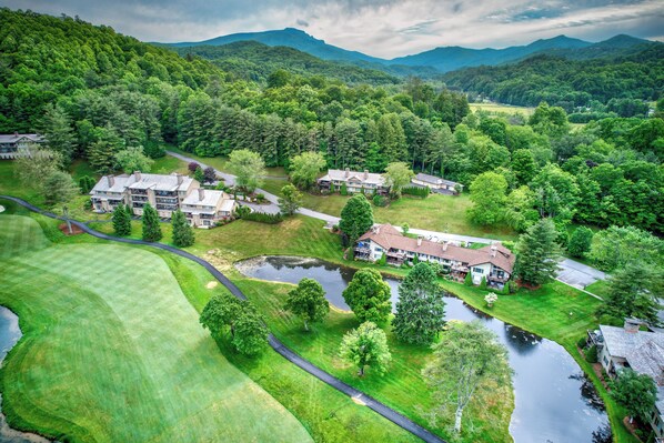 A residential area with multiple houses, a pond, and a golf course.