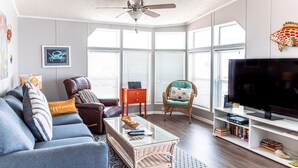 A living room with a sofa, armchairs, a coffee table, a TV, and a bookshelf.