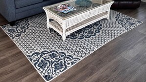 A living room with a dark grey sofa, a white coffee table, and a patterned rug.