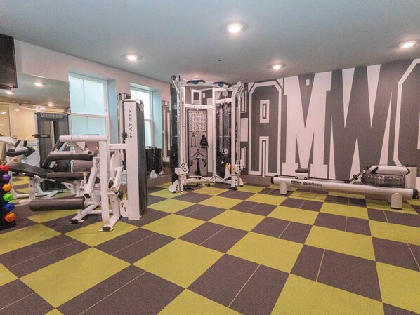 A gym with various exercise equipment, a checkered floor, and a wall with large letters. - Centre Court at 514 by Apex Short Term Stays (Oxford)