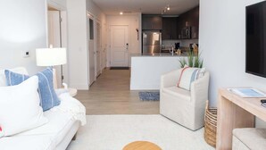 Una sala de estar moderna con un sofá, un sillón, una mesa de centro y un televisor montado en la pared.