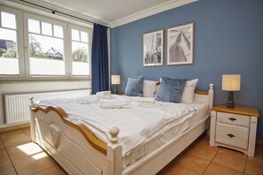 Ein Schlafzimmer mit einem Bett, zwei Nachttischen, einem Fenster und zwei Wandbildern.