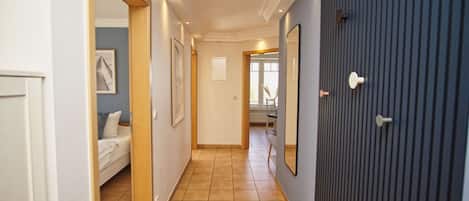 Un pasillo con una cama, cuadros enmarcados y una puerta de color oscuro.
