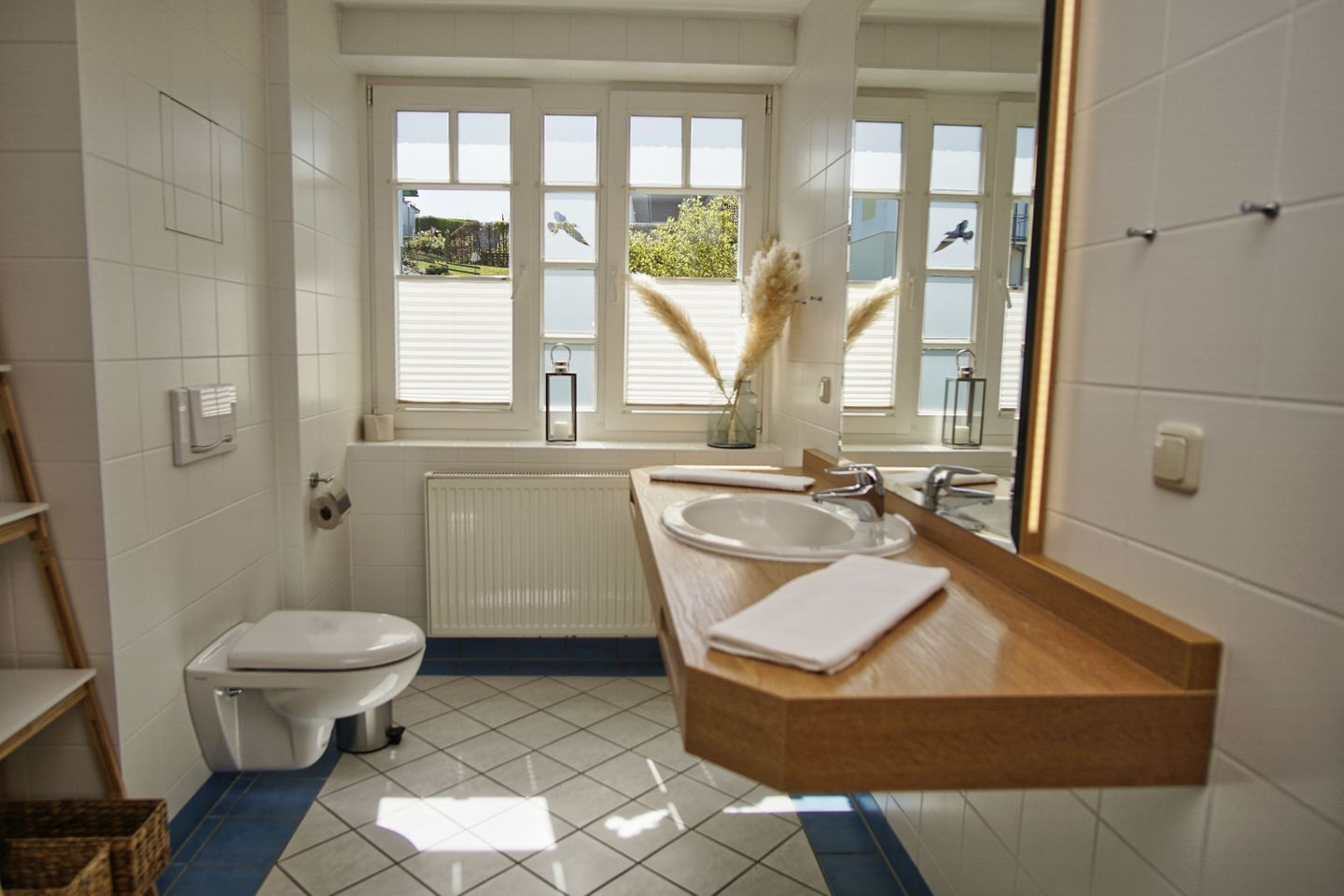 A modern bathroom with a toilet, sink, and large windows.