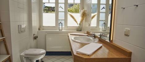 A modern bathroom with a toilet, sink, and large windows.