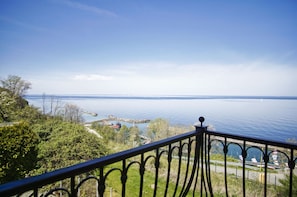 A balcony with a view of a calm sea and rocky outcrops.