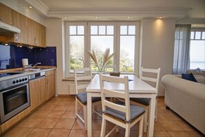 A compact kitchen with a dining area, a sofa, and a view of the outdoors. - Ferienwohnung mit Traumhaftem Meerblick - Haus am Meer Fewo 05 - Haus am Meer (Lohme)