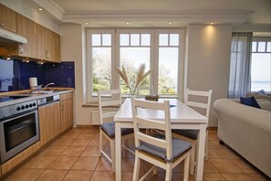 A compact kitchen with a dining area, a sofa, and a view of the outdoors.