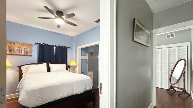 A bedroom with a bed, a ceiling fan, a nightstand, a lamp, and a wardrobe. - Broad Ripple 1 Bedroom  (Indianapolis)