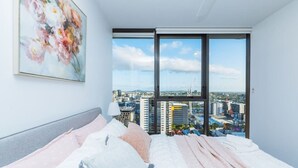 A modern bedroom with a large bed, a city view, and a painting on the wall. - 2BD Apt W/ Spectacular City Views/ Free carpark (South Brisbane)
