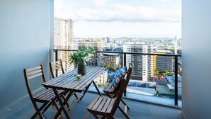 A balcony with a wooden table and chairs, a potted plant, and a city view. - 2BD Apt W/ Spectacular City Views/ Free carpark (South Brisbane)
