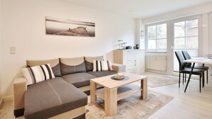 Ein modernes Wohnzimmer mit einer Couch, einem Couchtisch und einem Essbereich mit Stühlen.