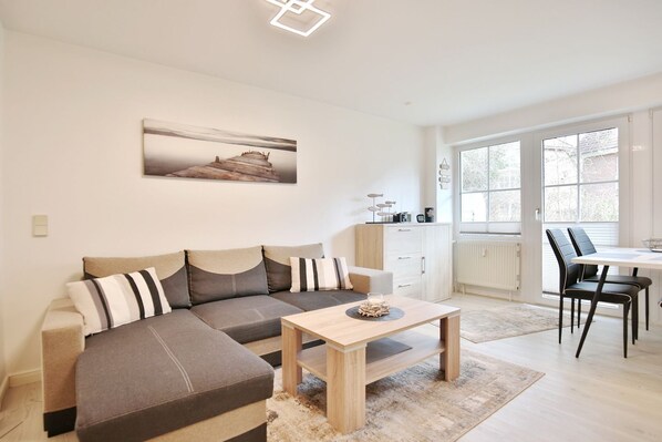 A modern living room with a sofa, a coffee table, and a dining area with chairs.
