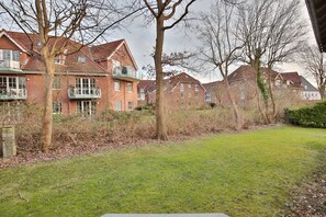 A residential area with brick houses, a grassy lawn, and leafless trees.