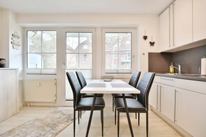 A modern kitchen with a dining table and chairs, large windows, and a view of the neighborhood.