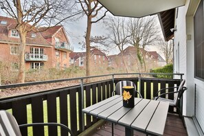 A balcony with a table and chairs, a decorative vase, and a view of residential buildings.
