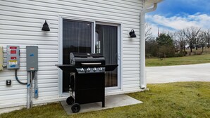 Ein Haus mit Grill vor einer Glasschiebetür, einer Solaranlage und blauem Himmel.