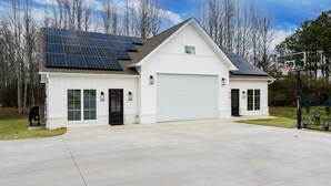 Eingeschossiges Haus mit weißer Fassade, einer Garage und Solaranlage auf dem Dach.