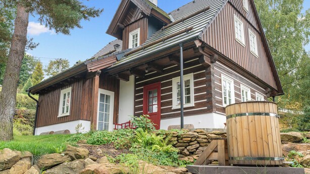 A log cabin with a red door, stone foundation, and a wooden barrel. - Roubenka Maleč by Interhome (Nezdice na Šumavě)