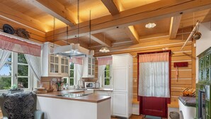 A cozy kitchen with wooden beams, a central island, and a dining area with a chair. - Roubenka Maleč by Interhome (Nezdice na Šumavě)