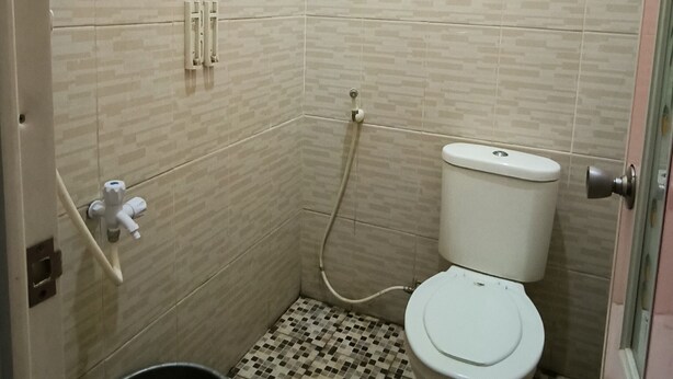 A small bathroom with a toilet, a shower, and a black bucket. - Pondok Kartini Jepara (Tahunan)