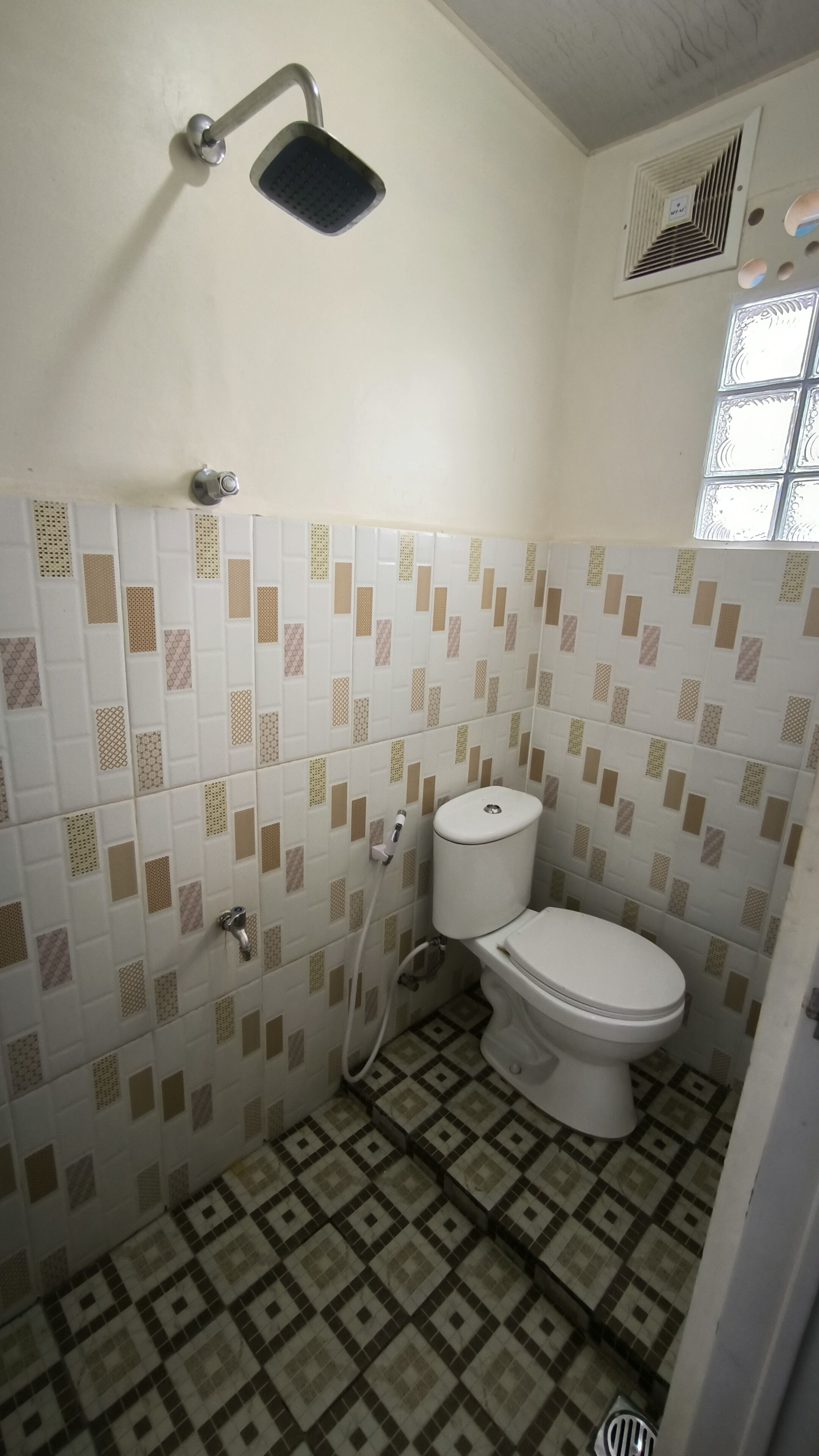Een compacte badkamer met toilet, douche en raam.