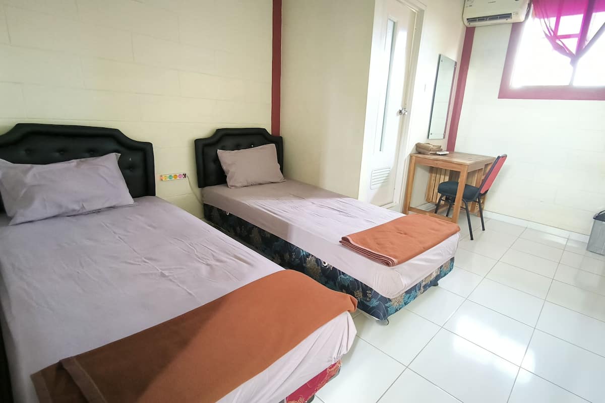 Een kamer met twee éénpersoonsbedden, een klein bureau met stoel en een raam met uitzicht.