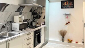 A modern kitchen with a marble backsplash, stainless steel appliances, and a small dining area with a vase of dried plants. - Apartment - Sleeps 4 - Parking - WiFi (Greater London, Dagenham)